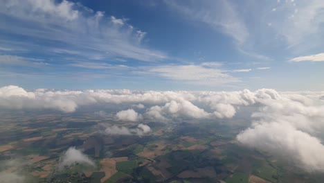 slow-flying-with-an-airplane-trough-the-clouds-and-flat-farm-land-of-Germany-visible-bellow
