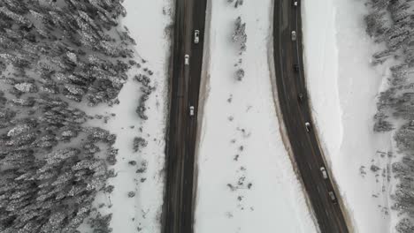 Winter-traffic-on-mountain-switchback-highway,-unique-aerial-angle
