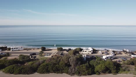 A-beautiful-aerial-drone-shot,-drone-flying-backwards-over-the-coast-and-beach-houses-with-a-view-of-the-horizon-and-ocean,-Carlsbad-State-Beach---California