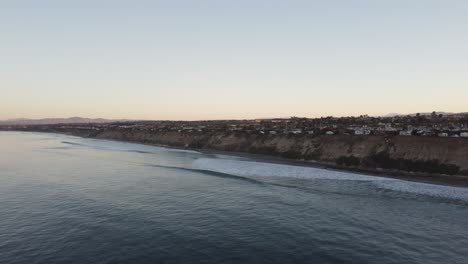 A-beautiful-aerial-drone-shot,-flying-along-the-coastline-during-golden-hour,-Carlsbad-State-Beach---California