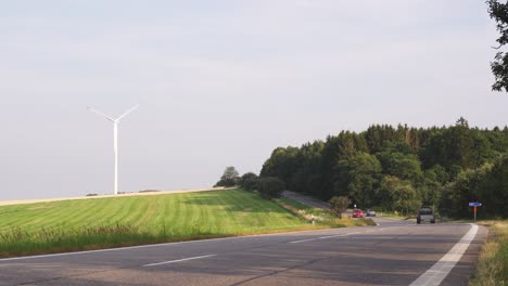 Autos-Fahren-Straße,-Windmühle-Im-Hintergrund,-Schnelle-Bewegung-Oder-Zeitraffer,-Statische-Kamera-Mit-Niedrigem-Winkel