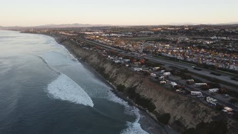 A-beautiful-aerial-drone-shot,-drone-flying-towards-the-coast-with-mountains-in-the-background,-Carlsbad-State-Beach---California
