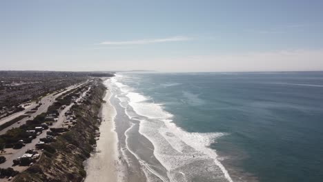 A-beautiful-aerial-drone-shot,-drone-flying-along-the-coast-over-the-beach,-Carlsbad-State-Beach---California