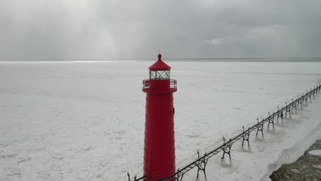 Grand-Haven,-Michigan-lighthouse-in-the-winter-at-Lake-Michigan-with-drone-circle-view