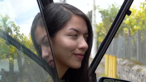 Schöne-Junge-Hispanische-Frau-Lächelt-Und-Schaut-In-Die-Kamera-Und-Sitzt-In-Einem-Auto