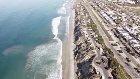 A-beautiful-aerial-drone-shot,-drone-flying-along-the-highway-over-to-the-beach,-Carlsbad-State-Beach---California