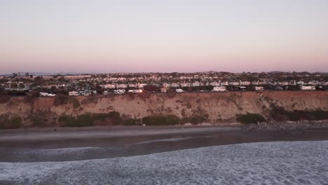 A-stunning-aerial-drone-shot,-flying-along-the-coast-during-golden-hour,-Carlsbad-State-Beach---California