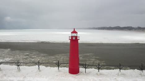 Grand-Haven,-Michigan-lighthouse-in-the-winter-at-Lake-Michigan-with-drone-pull-away