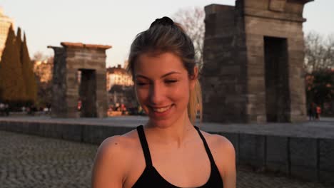 Selbstbewusste-Junge-Blonde-Fitness-Frau,-Die-Im-Stadtpark-In-Die-Kamera-Lächelt
