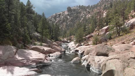 Low-aerial-follows-down-stream-in-Rocky-Cheesman-Canyon,-Colorado