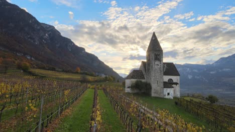 Aerial-Drone-Over-a-medieval-church-in-the-middle-of-the-Vineyards-in-Autumn-in-South-Tyrol