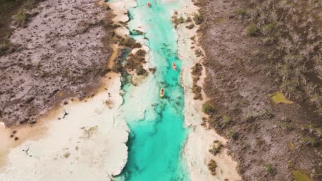 Upwards-panning-drone-shot-of-kayakers-revealing-the-scenic-view-of-"los-rapidos"-rapids-located-in-Bacalar,-Mexico-shot-in-4k