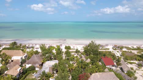 Wide-angle-drone-shot-panning-up-to-reveal-the-beautiful-white-sand-beaches-of-the-tropical-island-of-Holbox-in-Mexico-during-a-sunny-hot-day-with-resorts-and-hotels-in-the-distance-shot-in-4k