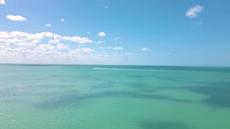 Wide-angle-drone-shot-approaching-a-boat-driving-on-the-crystal-clear-turquoise-waters-off-the-coast-of-Holbox-Island-in-the-Caribbean-sea-located-in-Mexico-shot-in-4k