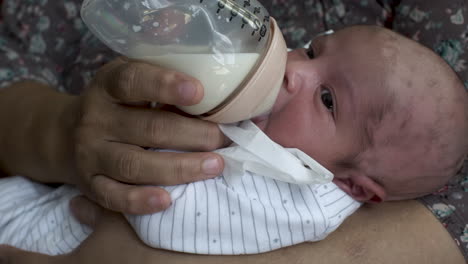 Nahaufnahme-Eines-Neugeborenen-Babys,-Das-In-Den-Armen-Seiner-Mutter-Liegt-Und-Sich-Von-Einer-Flasche-Muttermilch-Ernährt