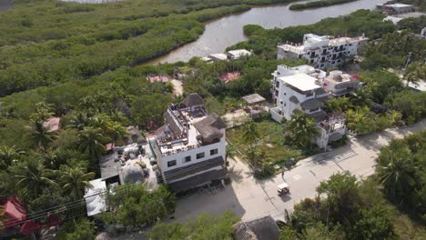 Wide-angle-drone-shot-panning-downwards-of-hotels-and-resorts-surrounded-by-a-jungle-and-mangroves-on-the-tropical-island-of-Holbox-in-Mexico-shot-in-4k