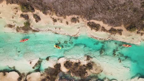 Bird's-eye-view-drone-shot-of-kayakers-going-through-the-los-rapidos"-rapids"-passageway-located-in-Bacalar,-Mexico-in-the-state-of-Quintana-Roo-in-4k