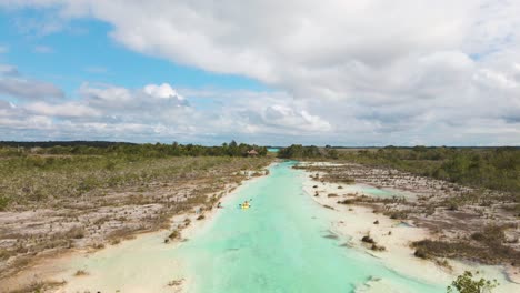 Wide-angle-drone-shot-revealing-the-beautiful-scene-of-kayakers-paddling-through-"los-rapidos"-rapids-canal-located-in-Bacalar,-Mexico-shot-in-4k