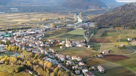 Aerial-Drone-Over-the-Vineyards-and-a-small-Valley-with-a-Church-in-the-center-in-Autumn-in-South-Tyrol