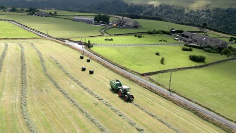 Green-Tractor-harvesting-hay-on-a-rural-English-landscape-aerial-view