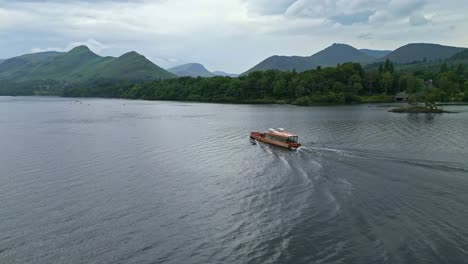 Drone-footage-of-Derwentwater,-Keswick,-a-calm-lake-with-river-boats-and-a-stormy-sky