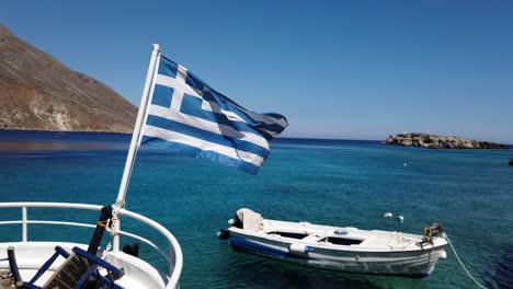 Greek-flag-fluttering-in-the-air-in-slow-motion-in-the-middle-of-the-sea-and-a-cloudless-blue-sky