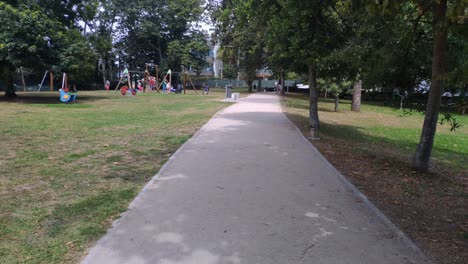 adults-with-children-enjoying-in-the-games-of-the-public-park-with-its-gardens-and-trees-a-sunny-summer-morning
