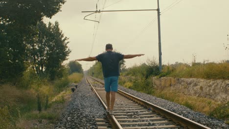 A-man-plays-tightrope-walker-on-the-tracks-of-a-train-at-a-possibly-abandoned-station
