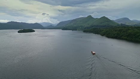 Drone-Aerial-footage-of-Derwentwater,-Keswick,-a-calm-lake-with-river-boats-and-a-stormy-sky