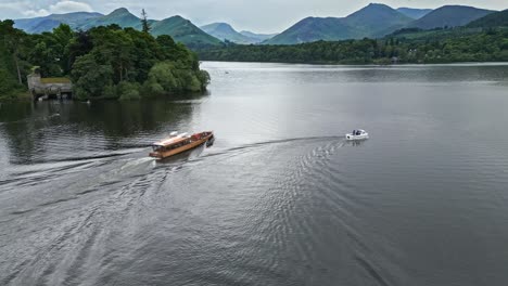 Drone-Aerial-footage-of-a-river-boat-on-Derwentwater,-Keswick,-a-calm-lake-with-river-boats-and-a-stormy-sky