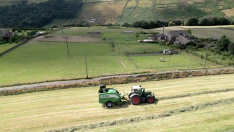 Green-Tractor-harvesting-hay-on-a-rural-landscape-aerial-view