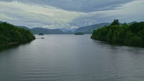 Drone-Aerial-footage-of-Derwentwater,-Keswick,-a-calm-lake-with-river-boats-and-a-stormy-sky