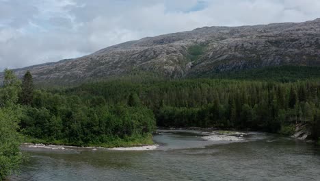 Vista-Aérea-Del-Río,-El-Bosque-Verde-Y-La-Montaña-Rocosa-A-La-Luz-Del-Día-En-El-Parque-Nacional-Lomsdal-visten-En-Noruega