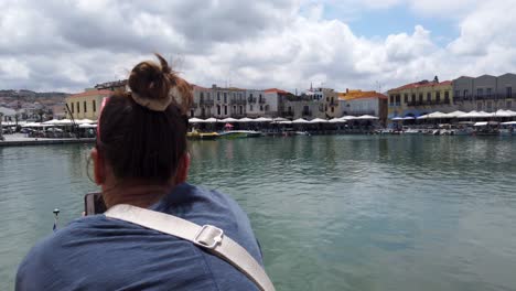 Touristenmädchen,-Das-Mit-Ihrem-Smartphone-Im-Querformat-Ein-Panoramabild-Des-Venezianischen-Hafens-Von-Rethimno-Macht
