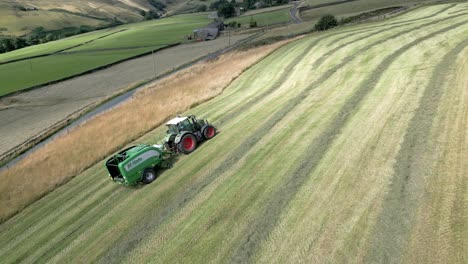 Beautiful-aerial-view-point-of-a-harvesting-tractor-with-black-roll-works-on-wide-grassy-field-in-summer