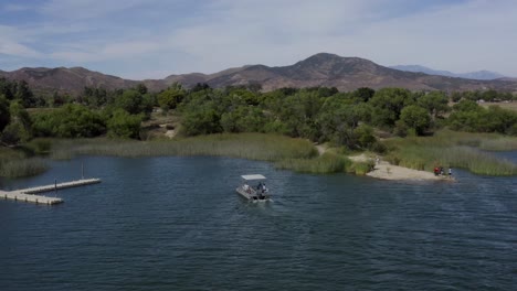 A-beautiful-aerial-drone-shot,-drone-tracking-a-boat-docking-in-the-marina-in-the-lake-in-Lake-Skinner---Temecula---Riverside-County---California