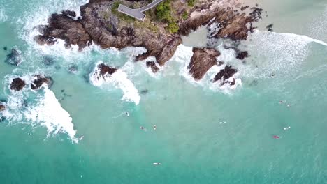 Drone-aerial-top-view-of-waves-and-surfers-enjoying-the-swell-in-Byron-Bay,-Australia
