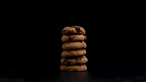 Stack-of-beautifully-cookies-vegetarian,-golden-brown-cookies-with-chocolate-rotating-against-a-black-background,-static-shot