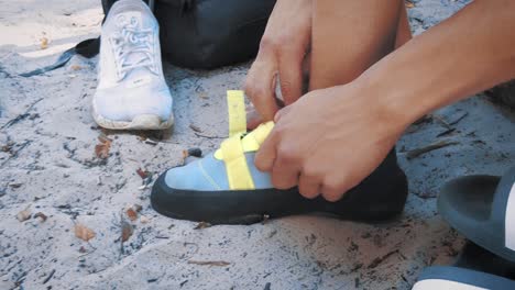 close-up-of-teenage-boy-switching-into-his-climbing-shoes-in-sand