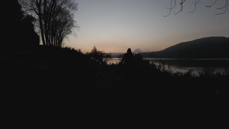 drone-shot-of-sunrise-by-the-lake-with-a-silhouette-of-a-visitor-and-his-motorbike