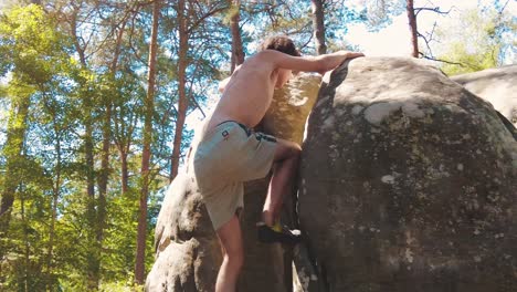 shirtless-teenage-boy-topping-a-boulder-in-pine-forrest-fontainebleau-sun-flares