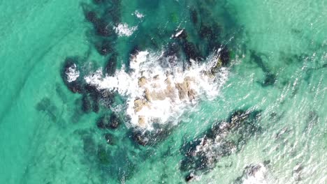 Drone-aerial-top-view-of-waves-breaking-into-some-rocks-in-the-middle-of-the-Pacific-Ocean