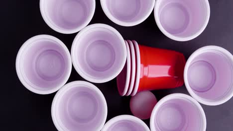 birdyeye-shot-with-rotating-beerpong-cups-with-white-ball-on-black-background
