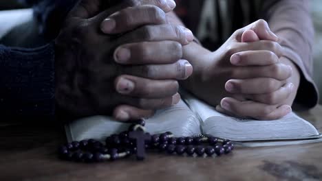 praying-to-God-with-hand-on-bible-black-background-with-people-stock-footage