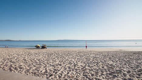 Lifeguard-Buggy-On-Sandy-Beach-Shore-Beside-Flat-Blue-Ocean-In-Morning-Light,-4K-Slow-Motion