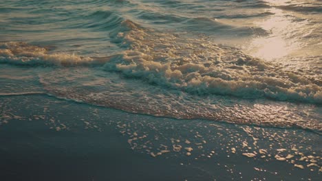 Waves-washing-up-on-beach-during-sunset,-slow-motion