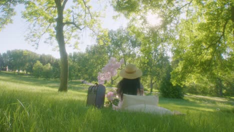 Lady-wears-straw-hat-in-shade-of-trees---picnic-in-park