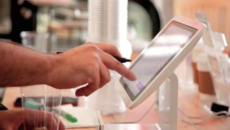 Cashier-ringing-up-an-order-on-tablet-POS-point-of-sale-system-in-local-small-business