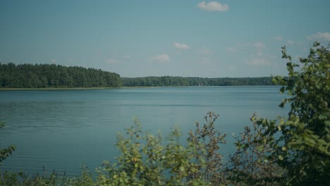 Peaceful-Lithuanian-forest-lake-under-blue-skies-and-sparse-clouds