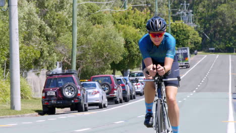Fit-Female-Cyclist-In-Lycra-Riding-Bike-Through-Suburban-Street,-4K-Slow-Motion